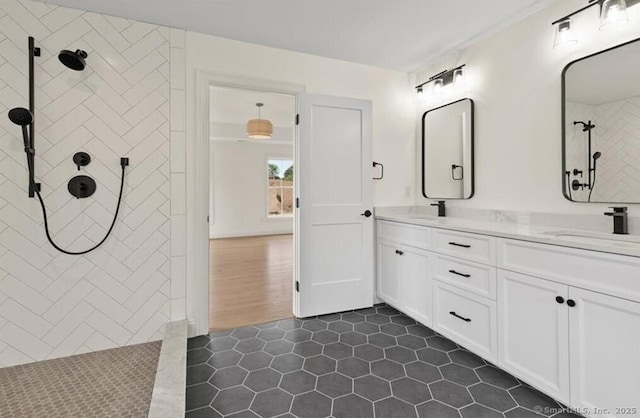 bathroom featuring double vanity, tiled shower, a sink, and tile patterned flooring