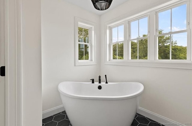 full bathroom with a freestanding tub, baseboards, and tile patterned flooring