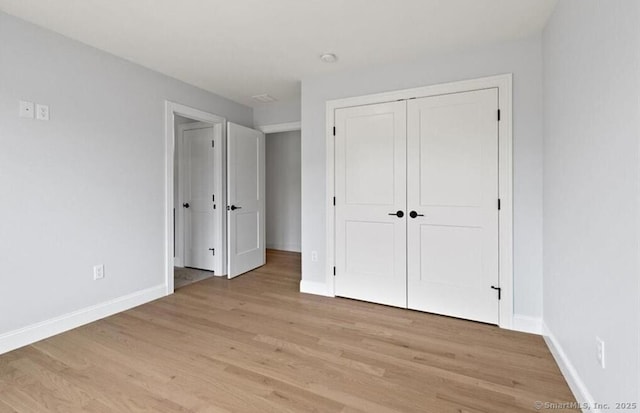 unfurnished bedroom with baseboards, a closet, and light wood-style flooring