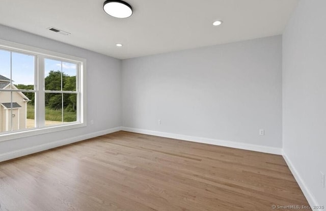 empty room featuring visible vents, recessed lighting, baseboards, and wood finished floors