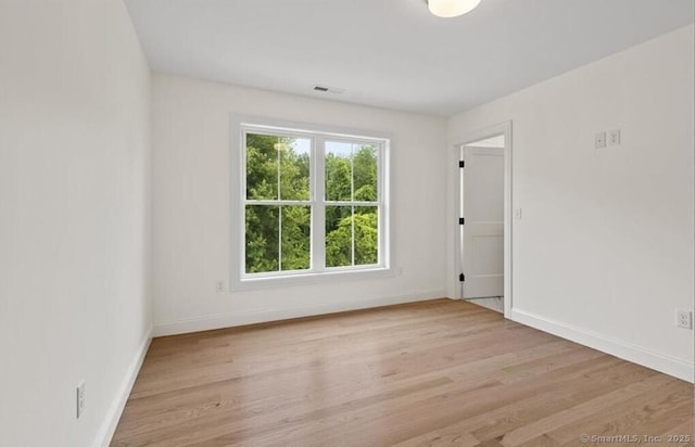 empty room featuring baseboards, light wood-type flooring, and visible vents
