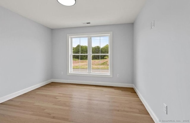 spare room with visible vents, baseboards, and wood finished floors