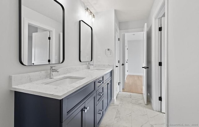 bathroom with double vanity, a sink, marble finish floor, and baseboards