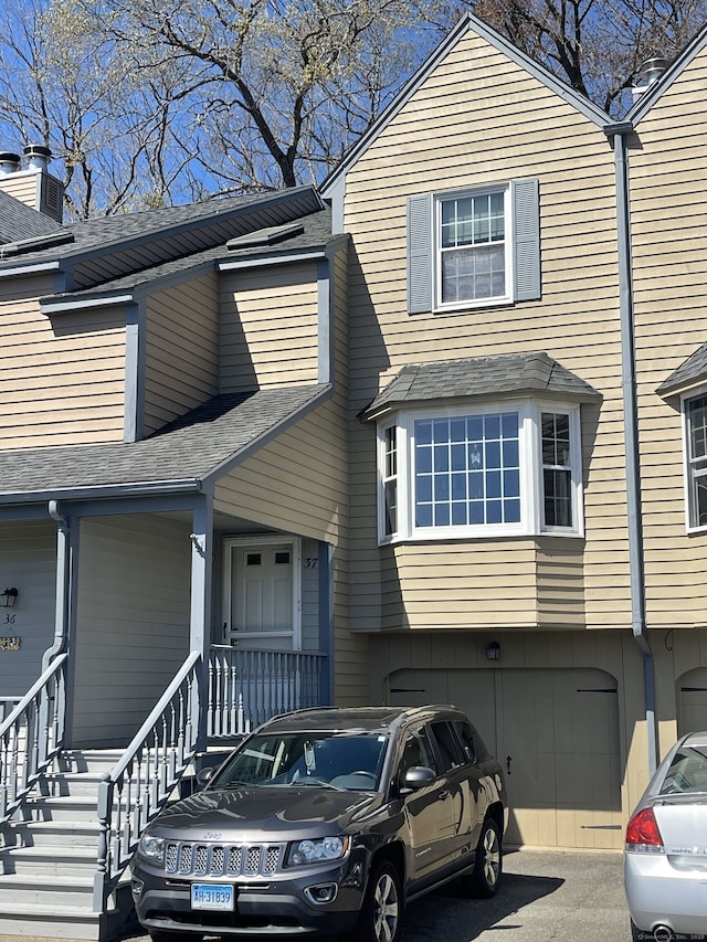 view of property featuring roof with shingles and a garage