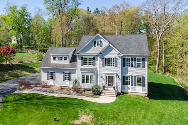 exterior space featuring a lawn and a shingled roof