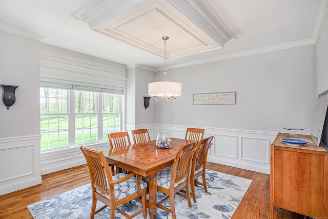 dining room with ornamental molding, a decorative wall, and wood finished floors