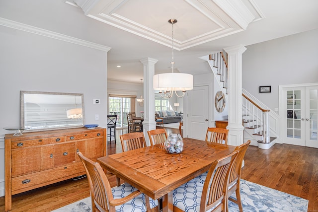 dining space featuring stairs, ornate columns, ornamental molding, and wood finished floors