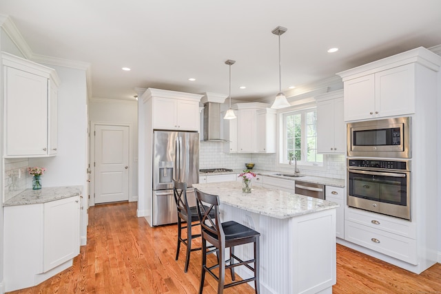 kitchen featuring a sink, white cabinetry, wall chimney range hood, and stainless steel appliances