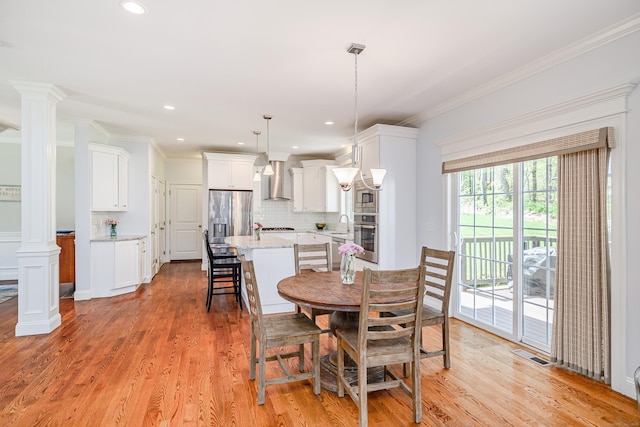 dining space with ornate columns, visible vents, and light wood finished floors