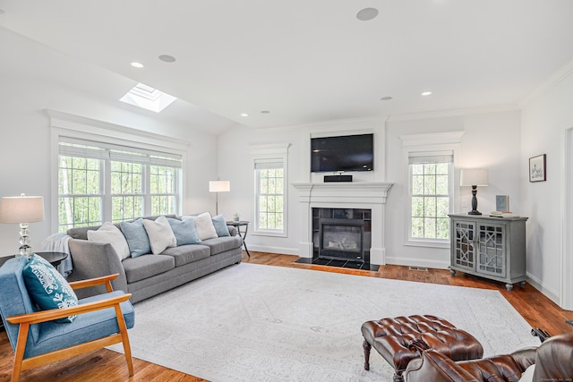 living room with visible vents, ornamental molding, wood finished floors, baseboards, and a tiled fireplace