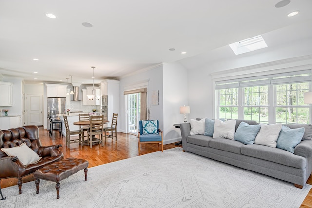 living room featuring crown molding, recessed lighting, wood finished floors, and a skylight