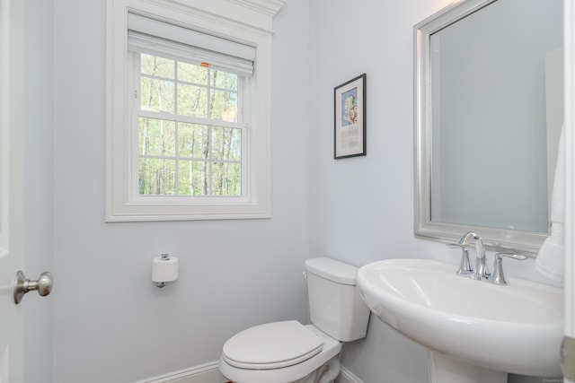 half bath with a sink, baseboards, and toilet
