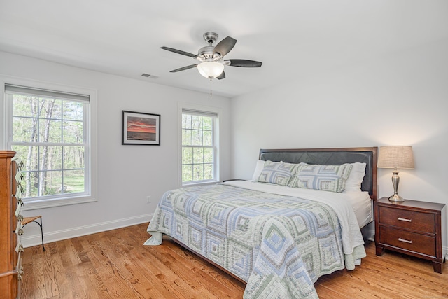 bedroom featuring ceiling fan, baseboards, visible vents, and wood finished floors
