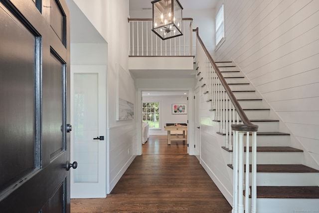 entryway with stairs, wood finished floors, a chandelier, and a towering ceiling