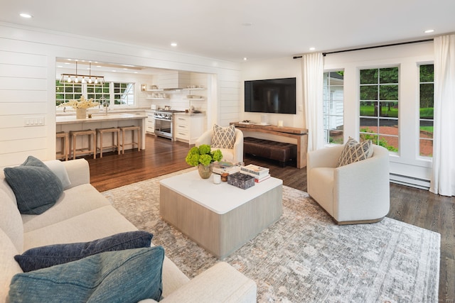 living area with a baseboard heating unit, wood finished floors, and recessed lighting