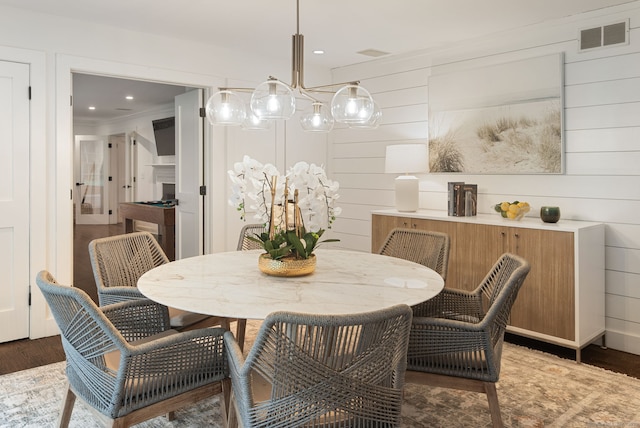 dining area featuring wood finished floors, ornamental molding, recessed lighting, and wooden walls