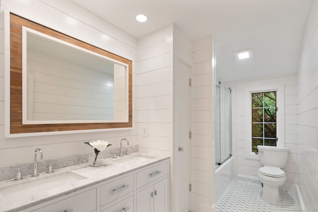 bathroom featuring toilet, double vanity, combined bath / shower with glass door, and tile patterned floors