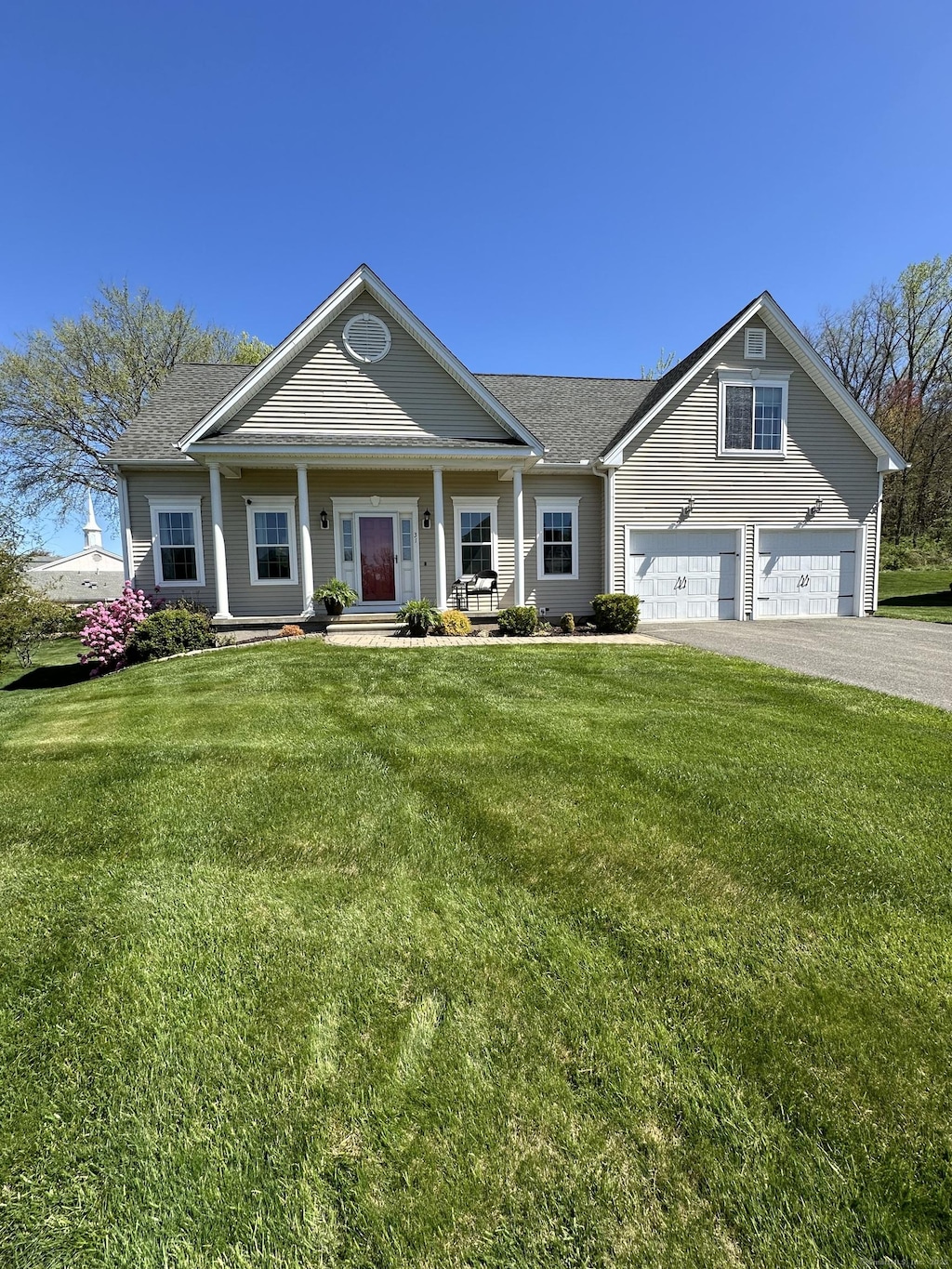 craftsman-style home featuring a shingled roof, a front lawn, aphalt driveway, a garage, and covered porch