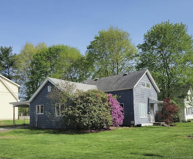 view of home's exterior with a lawn, a shingled roof, and a carport