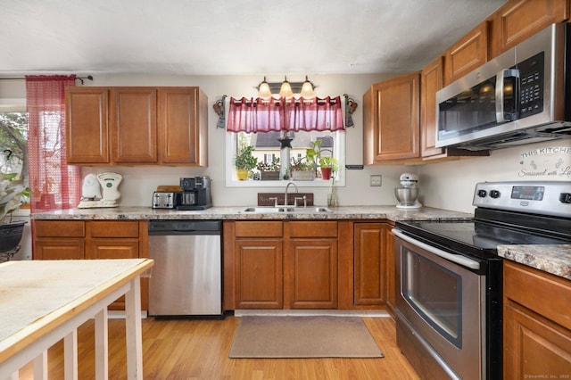 200 Mechanic St, Killingly, CT 06239 - kitchen featuring stainless steel appliances, a sink, light wood-style floors, and brown cabinets