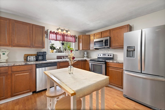 200 Mechanic St, Killingly, CT 06239 - kitchen featuring stainless steel appliances, brown cabinetry, light wood finished floors, and a sink