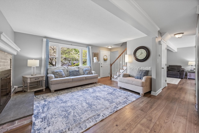 living area featuring stairs, wood finished floors, a brick fireplace, baseboards, and a baseboard heating unit
