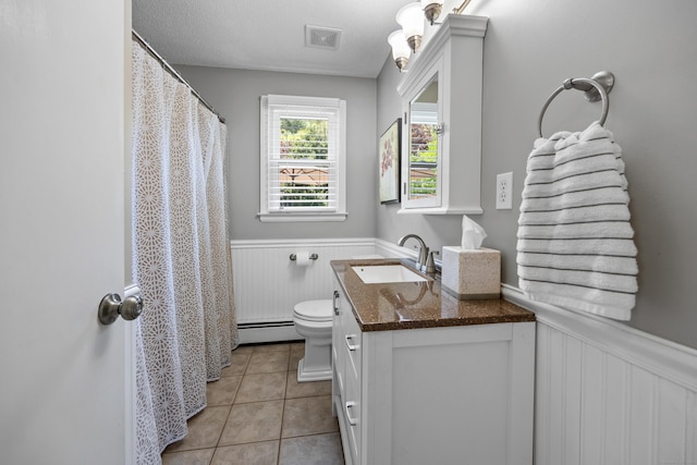 bathroom featuring wainscoting, a baseboard heating unit, toilet, vanity, and tile patterned flooring