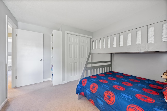 carpeted bedroom with a closet and baseboards