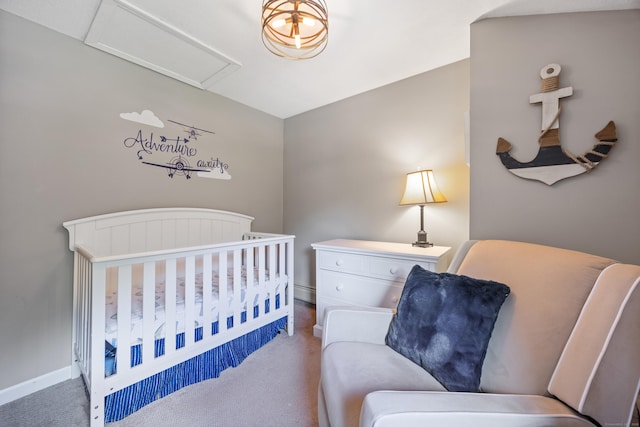 carpeted bedroom with attic access, a crib, and baseboards