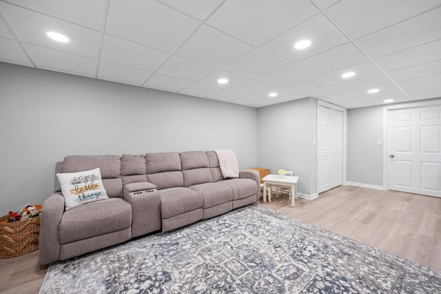 living area featuring wood finished floors, a paneled ceiling, recessed lighting, and baseboards