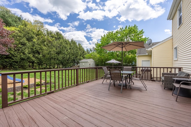 deck featuring a storage shed, outdoor dining space, an outdoor structure, and a yard
