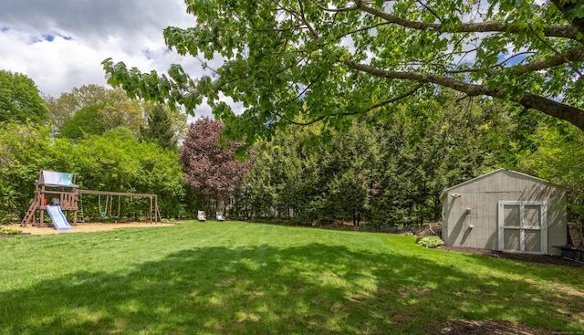 view of grassy yard with a storage shed, a playground, and an outbuilding