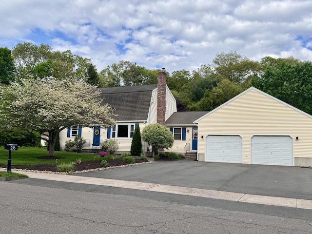 colonial inspired home featuring a garage, roof with shingles, asphalt driveway, a chimney, and entry steps