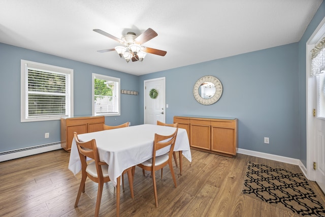 dining space featuring ceiling fan, light wood-style floors, baseboards, and a baseboard heating unit