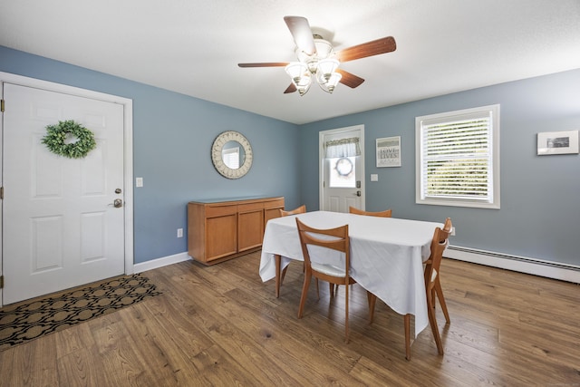 dining room featuring a baseboard heating unit, wood finished floors, ceiling fan, and baseboards