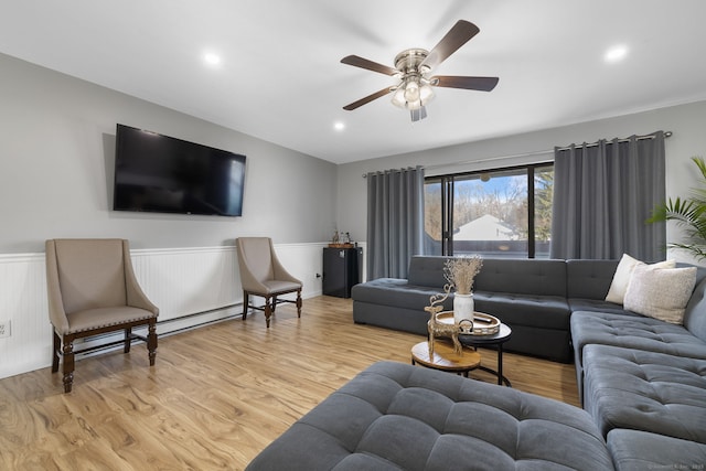 living room featuring a baseboard radiator, a wainscoted wall, recessed lighting, light wood finished floors, and a ceiling fan