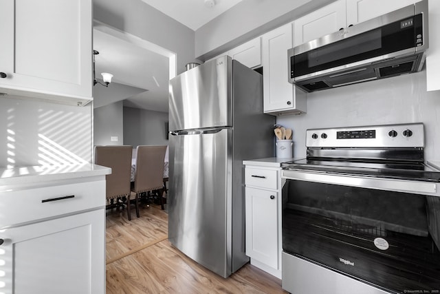 kitchen with white cabinets, light countertops, appliances with stainless steel finishes, and light wood-style flooring