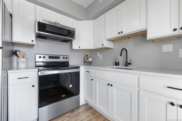 kitchen featuring appliances with stainless steel finishes, light countertops, white cabinets, and a sink