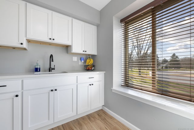 interior space with a healthy amount of sunlight, light wood-type flooring, baseboards, and a sink