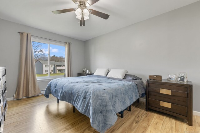 bedroom with baseboards, light wood-type flooring, and ceiling fan