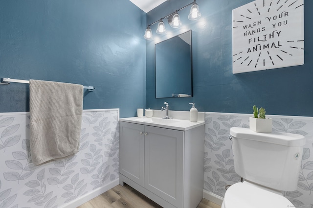 bathroom featuring toilet, vanity, wainscoting, and wood finished floors