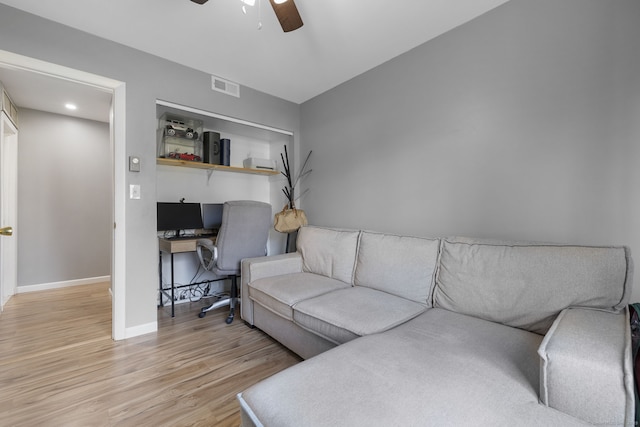 living area with light wood-type flooring, visible vents, ceiling fan, and baseboards