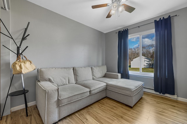 living room featuring ceiling fan, light wood-type flooring, a baseboard heating unit, and baseboards