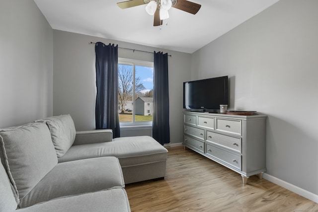 living area with a ceiling fan, baseboards, lofted ceiling, and light wood-type flooring