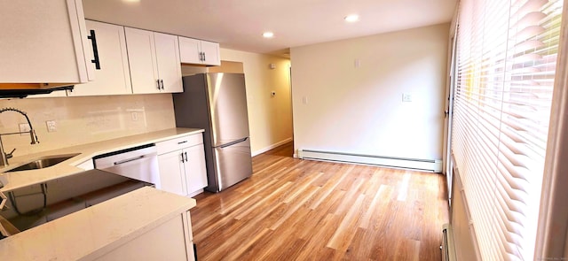 kitchen with white cabinets, stainless steel appliances, a sink, and a baseboard radiator