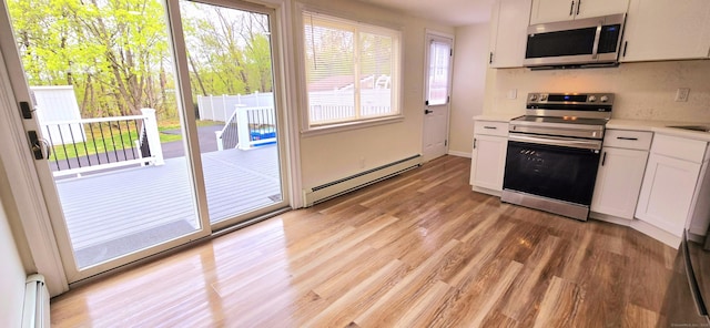 kitchen with light countertops, appliances with stainless steel finishes, baseboard heating, and light wood-type flooring
