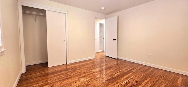 unfurnished bedroom featuring baseboards, wood finished floors, and a closet