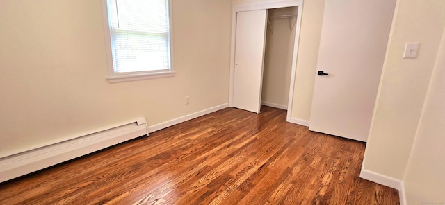 unfurnished bedroom featuring baseboards, wood finished floors, baseboard heating, and a closet