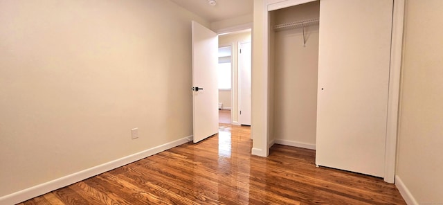 unfurnished bedroom with baseboards, a closet, and wood finished floors