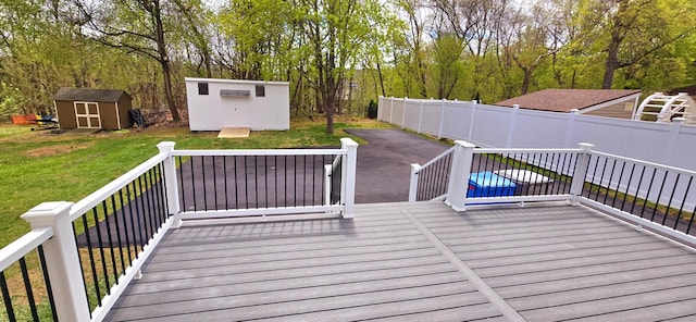 wooden deck with a yard, fence, an outbuilding, and a shed